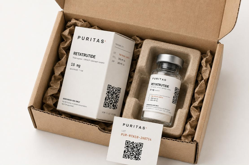 An opened kraft mailer as it arrives, containing a Puritas Retatrutide carton, a vial seated in a moulded pulp tray, and a lot card. Carton and vial both read RETATRUTIDE, 10 mg lyophilized, LOT PUR-RTA10-260714, FILL 2026-07-14, EXP 2029-07-14 and RESEARCH USE ONLY.